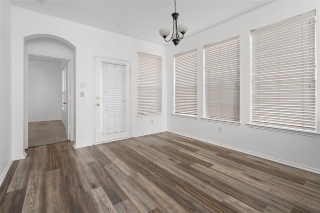 unfurnished dining area with a chandelier and dark hardwood / wood-style floors