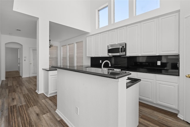 kitchen featuring white cabinets, decorative backsplash, and a kitchen island with sink