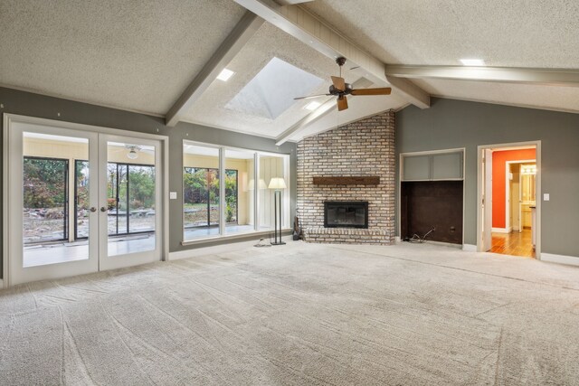 unfurnished living room featuring a textured ceiling, light colored carpet, lofted ceiling with skylight, ceiling fan, and a fireplace