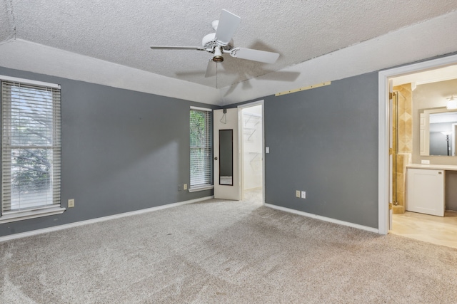 unfurnished bedroom with a textured ceiling, ceiling fan, light carpet, and connected bathroom