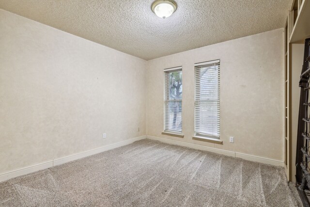 carpeted empty room with a textured ceiling