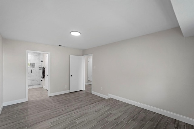 unfurnished bedroom featuring wood-type flooring and ensuite bath