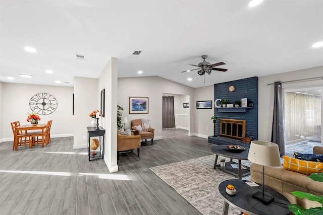 living room featuring ceiling fan, a fireplace, vaulted ceiling, and hardwood / wood-style flooring