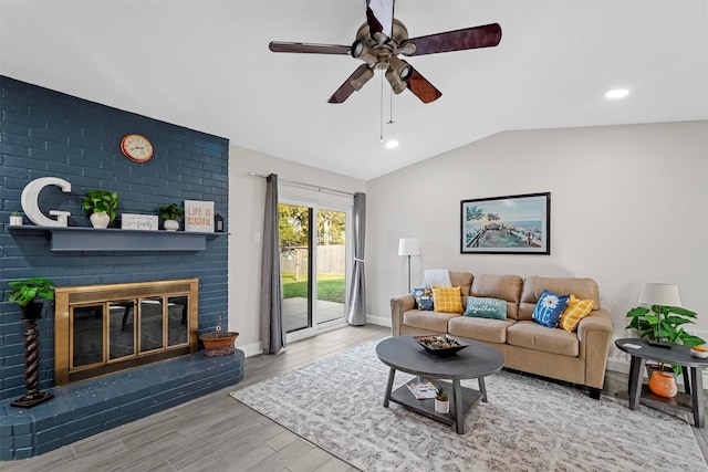 living room featuring ceiling fan, light hardwood / wood-style floors, a fireplace, and vaulted ceiling