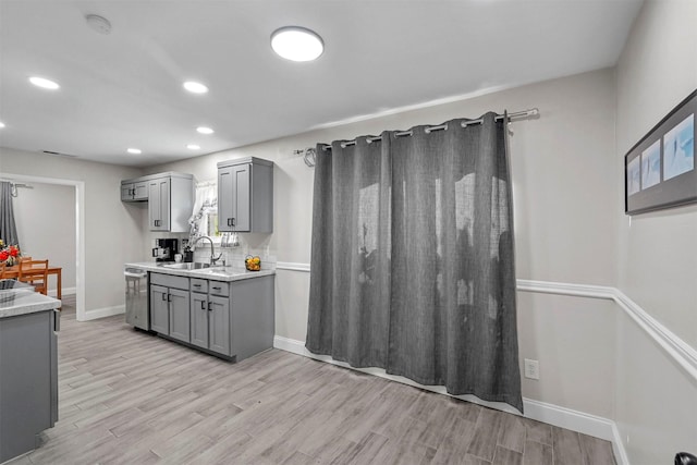 kitchen featuring gray cabinetry, dishwasher, light wood-type flooring, and sink