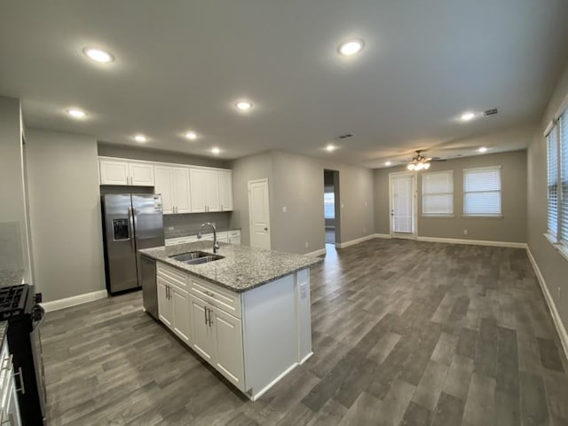 kitchen featuring light stone counters, stainless steel appliances, a kitchen island with sink, sink, and white cabinets