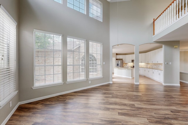 unfurnished living room featuring a towering ceiling and hardwood / wood-style flooring