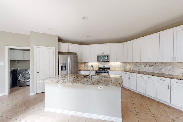 kitchen featuring washer / dryer, sink, an island with sink, and appliances with stainless steel finishes