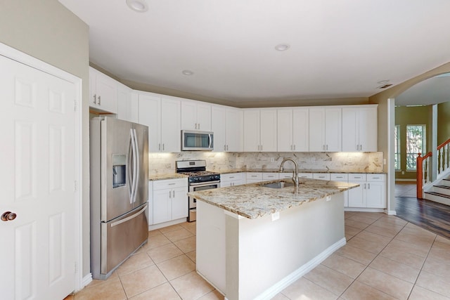 kitchen with white cabinets, stainless steel appliances, and a kitchen island with sink