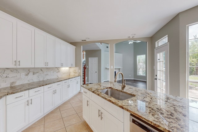 kitchen with light stone countertops, dishwasher, sink, decorative backsplash, and white cabinets