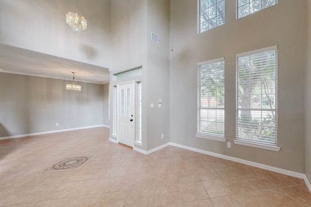 tiled entryway with crown molding, plenty of natural light, a high ceiling, and a notable chandelier