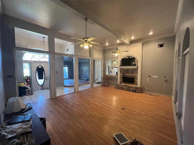 living room featuring a brick fireplace, crown molding, beam ceiling, and wood finished floors