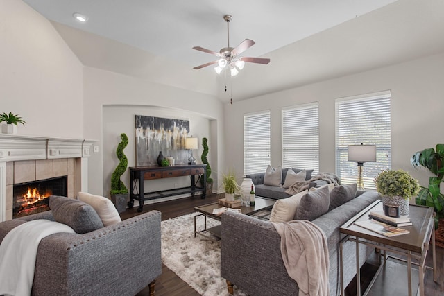 living room featuring a tile fireplace, ceiling fan, dark wood-type flooring, and lofted ceiling