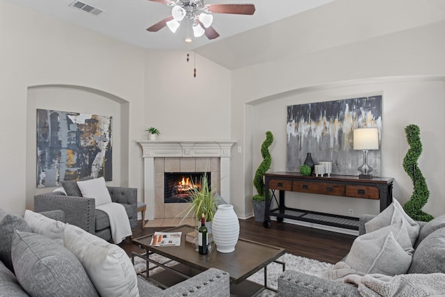 living room featuring ceiling fan, dark wood-type flooring, and a tile fireplace