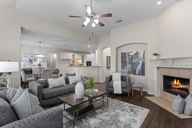 living room featuring hardwood / wood-style floors, ceiling fan, a tile fireplace, and vaulted ceiling