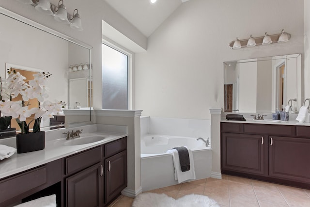 bathroom with tile patterned flooring, vanity, a bath, and vaulted ceiling