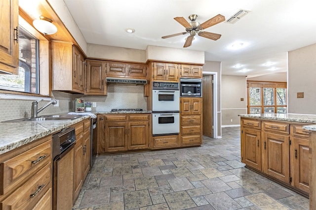 kitchen featuring light stone counters, backsplash, stainless steel appliances, and sink