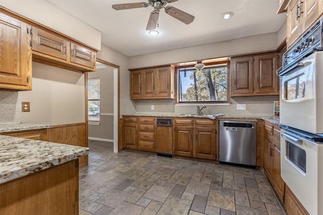 kitchen featuring plenty of natural light, sink, stainless steel dishwasher, and light stone counters