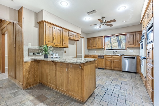 kitchen with a kitchen breakfast bar, kitchen peninsula, ceiling fan, stainless steel appliances, and decorative backsplash