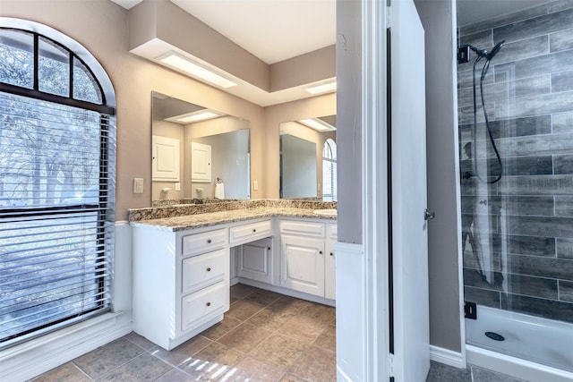 bathroom featuring a shower with door and vanity