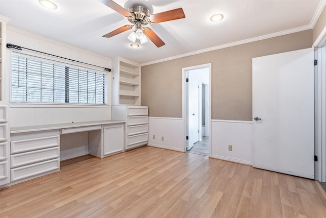 unfurnished office with crown molding, ceiling fan, built in desk, light hardwood / wood-style floors, and built in shelves