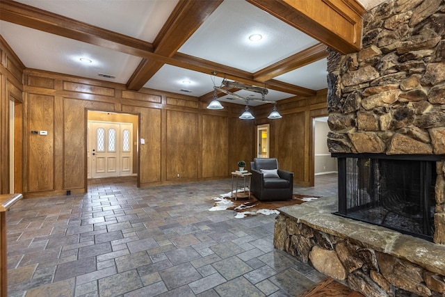 unfurnished living room featuring coffered ceiling, a stone fireplace, wooden walls, and beamed ceiling