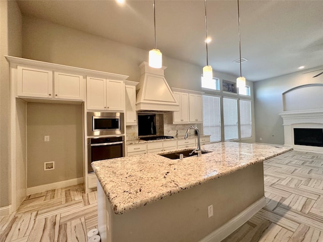 kitchen featuring sink, a center island with sink, decorative light fixtures, and appliances with stainless steel finishes