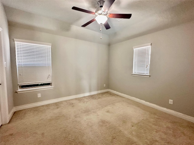 carpeted spare room featuring a raised ceiling and ceiling fan