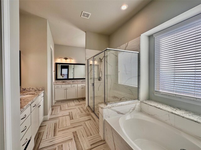 bathroom featuring plus walk in shower, vanity, and parquet flooring