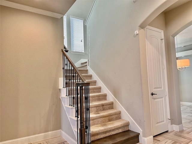 stairway with parquet flooring and ornamental molding