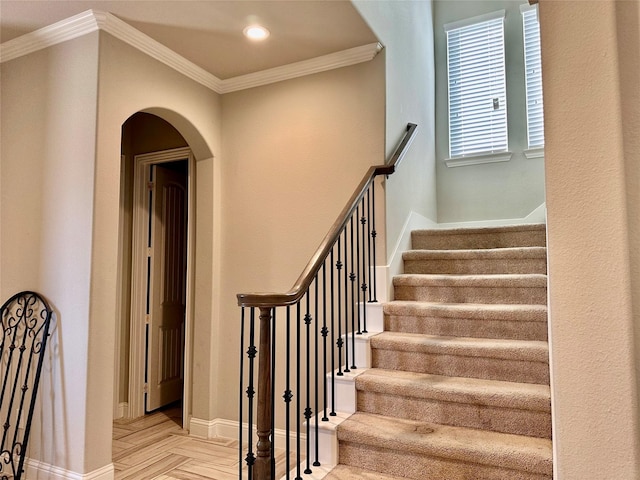 stairway with crown molding and parquet flooring