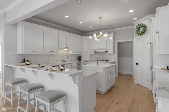 kitchen featuring pendant lighting, white cabinets, kitchen peninsula, crown molding, and light hardwood / wood-style flooring