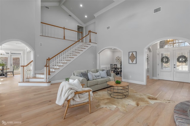 living room featuring french doors, ornamental molding, high vaulted ceiling, and light hardwood / wood-style flooring