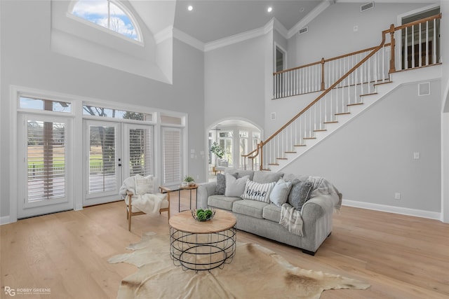 living room featuring french doors, crown molding, light hardwood / wood-style floors, and a wealth of natural light