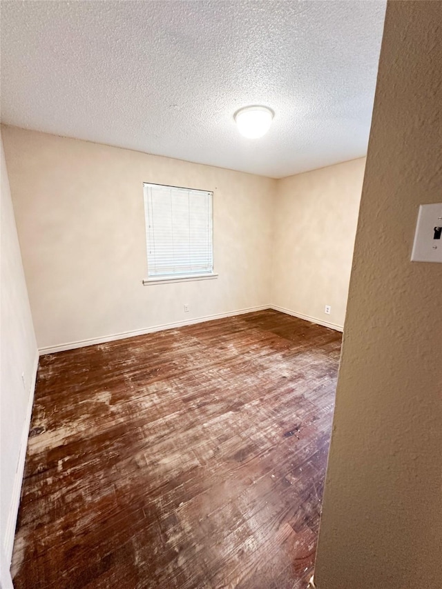 empty room with dark hardwood / wood-style flooring and a textured ceiling