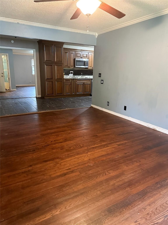 unfurnished living room with crown molding, ceiling fan, dark wood-type flooring, and a textured ceiling