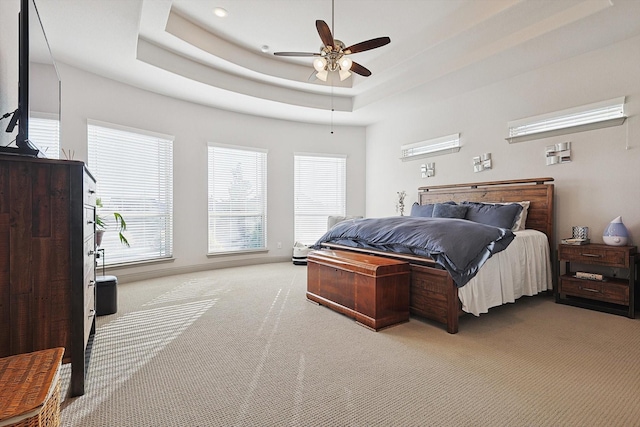 carpeted bedroom with a tray ceiling and ceiling fan