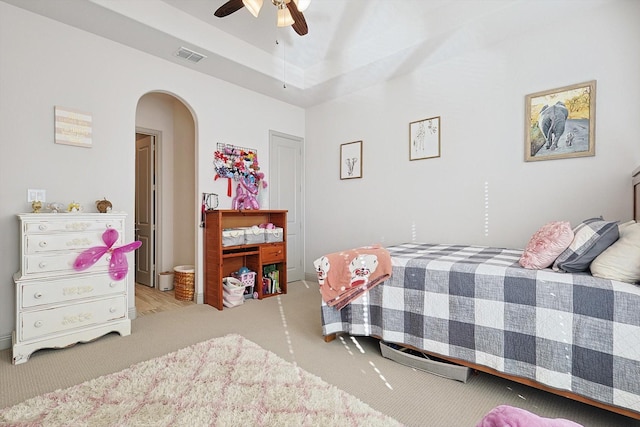 bedroom with a tray ceiling, ceiling fan, and light carpet