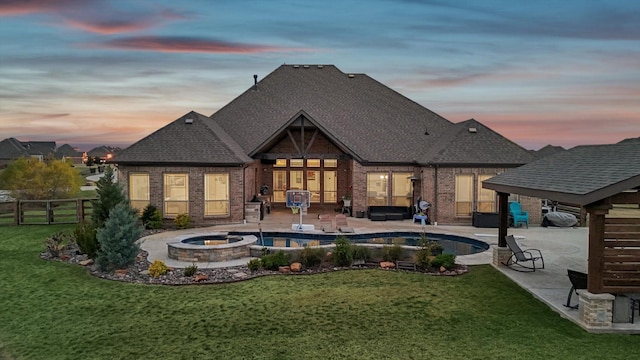 back house at dusk featuring an outdoor fire pit, a pool with hot tub, a patio area, and a lawn