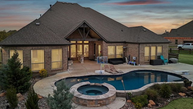 back house at dusk featuring a patio area and a pool with hot tub