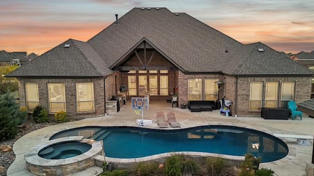 back house at dusk with a pool with hot tub and a patio