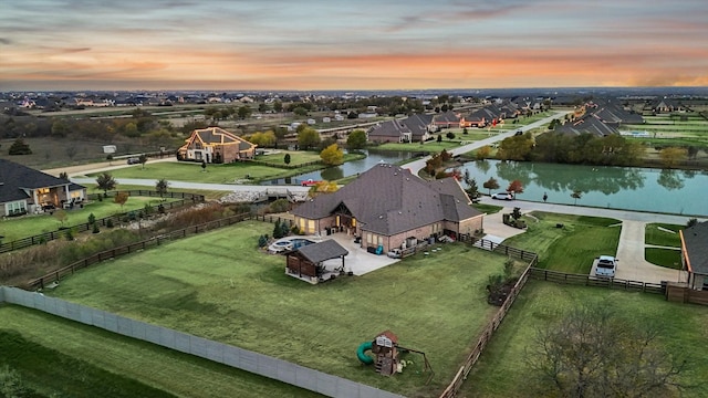 aerial view at dusk featuring a water view