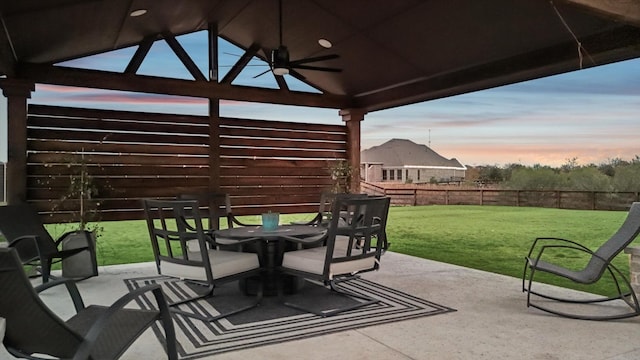 patio terrace at dusk with a gazebo, ceiling fan, and a lawn