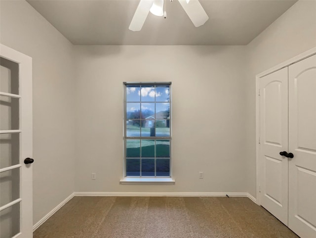 unfurnished bedroom with ceiling fan, dark carpet, and a closet