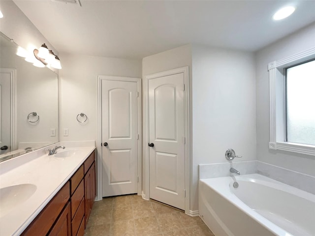 bathroom with a bathing tub, vanity, and tile patterned flooring