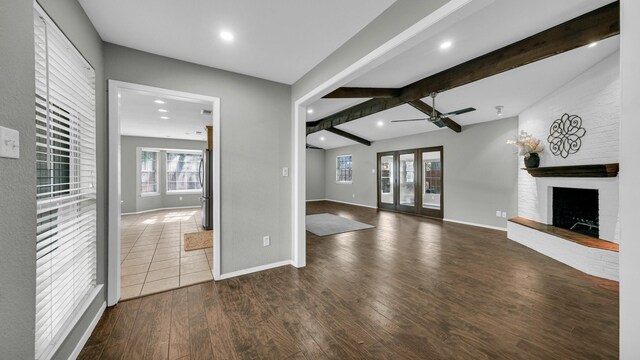 unfurnished living room with beamed ceiling, dark hardwood / wood-style floors, and a healthy amount of sunlight