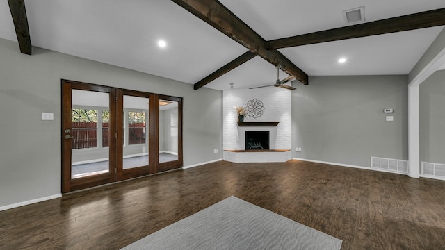 unfurnished living room featuring french doors, dark hardwood / wood-style flooring, ceiling fan, a fireplace, and vaulted ceiling with beams