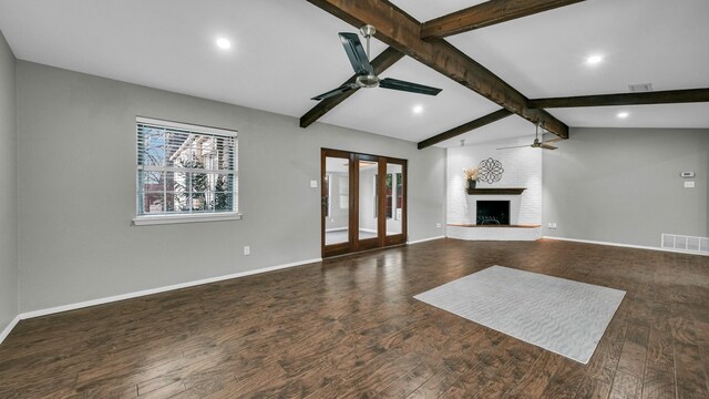 unfurnished living room featuring french doors, a brick fireplace, ceiling fan, lofted ceiling with beams, and dark hardwood / wood-style floors