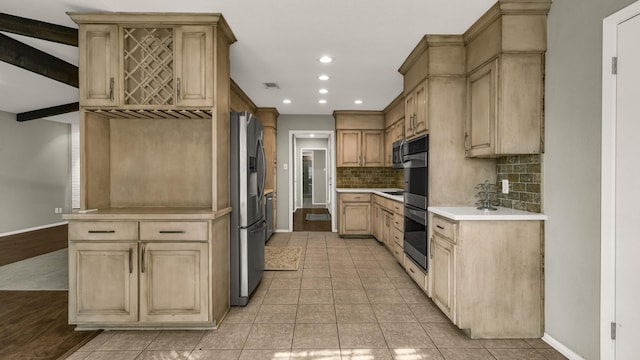 kitchen featuring decorative backsplash, light brown cabinetry, light tile patterned flooring, and appliances with stainless steel finishes