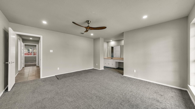 unfurnished bedroom featuring ensuite bathroom, carpet, built in desk, and ceiling fan